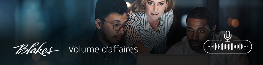 Bannière web Volume d'affaires, comportant le texte « Volume d'affaires » sur un fond bleu foncé avec un paysage urbain flou en arrière-plan et trois personnes regroupées autour d'un ordinateur.
