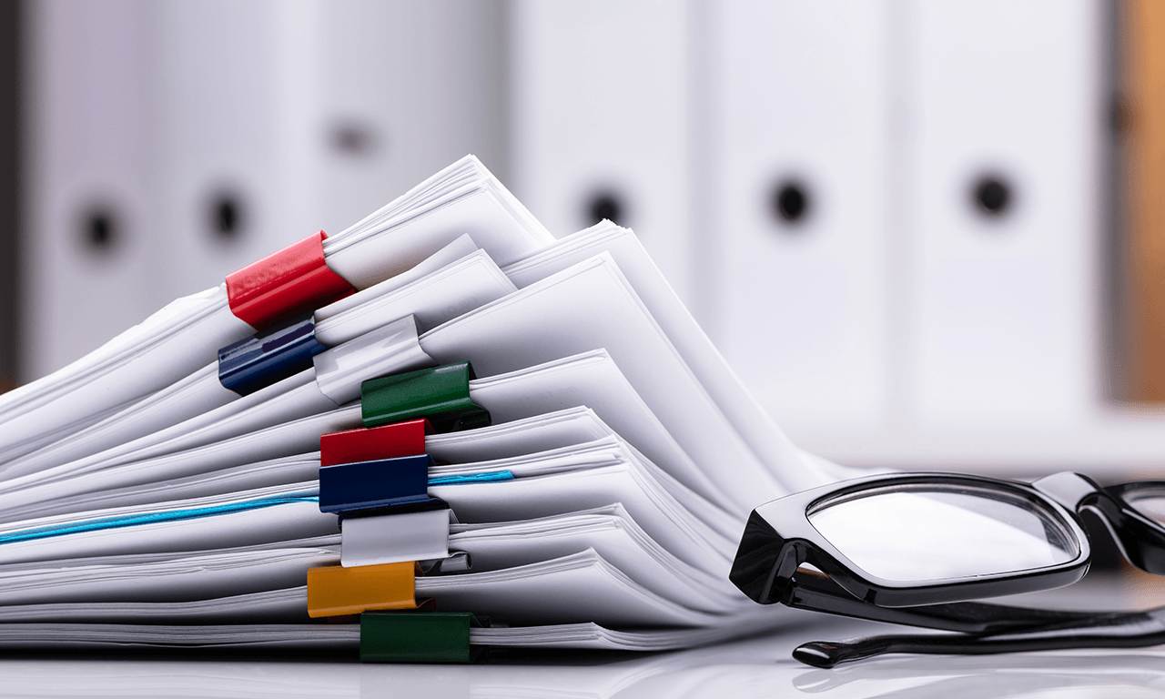 Stack of papers with reading glasses